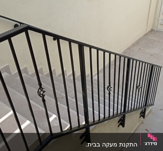 מעקה מתכת שחור לאורך מדרגות בטון אפורות